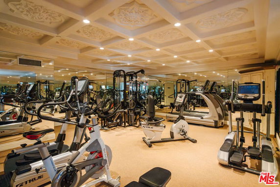 Indoor gym area with various fitness equipment and mirrored walls.