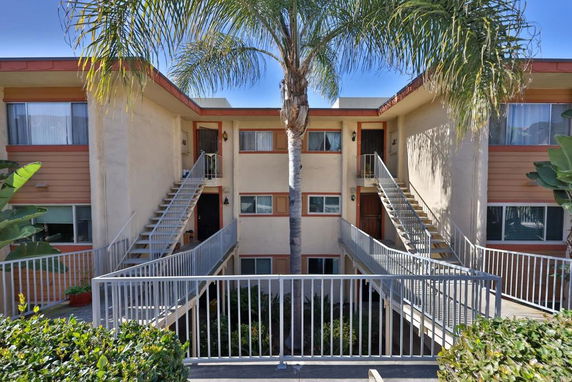 Front view of a multi-story apartment building with external staircases and balconies.