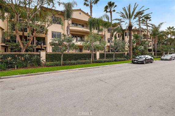 Front view of a multi-story residential building with balconies and surrounding trees.