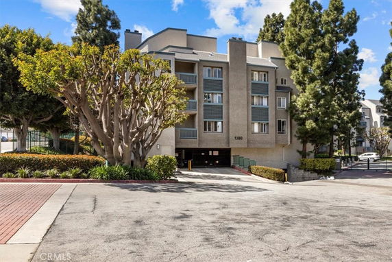 Front view of a multi-story apartment building with gated parking.