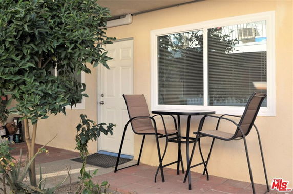 Front view of a house with a small patio area featuring a round table and two chairs.