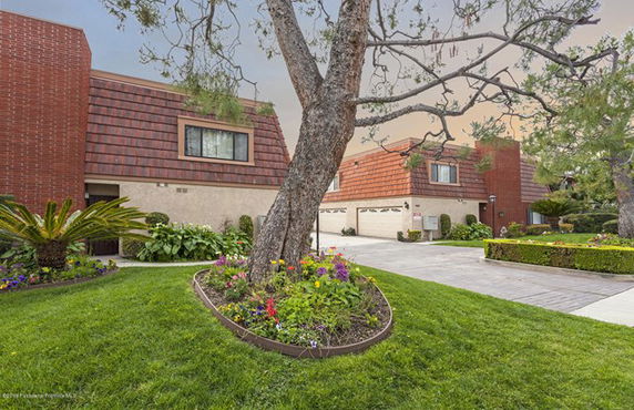 Front view of residential buildings with brick and shingle exteriors and landscape features.