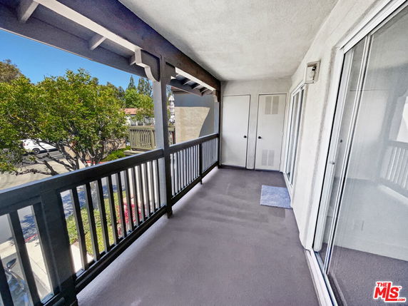 Balcony view showing railing and part of a residential street with trees.