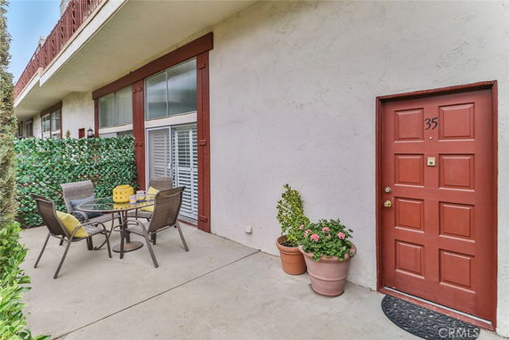 Front view of a building entrance with a patio area, table, and chairs.