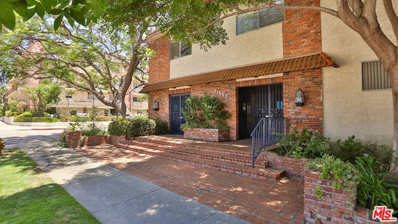 Front view of a brick and stucco multi-story building with an entrance and staircase.