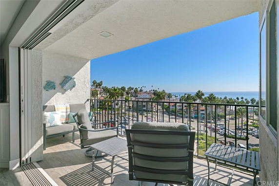 View from a balcony overlooking a coastal area with palm trees and ocean.