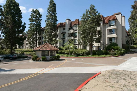 Front view of a multi-story residential building with a tiled roof and surrounding trees.
