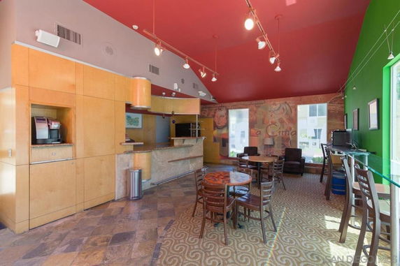 Interior of a recreation area with tables, chairs, and a coffee station.