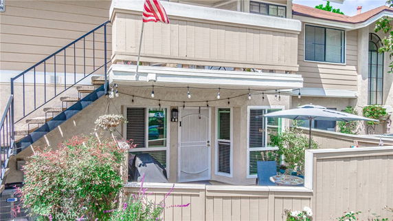 Front view of a two-story house with an outdoor staircase and a small fenced patio.