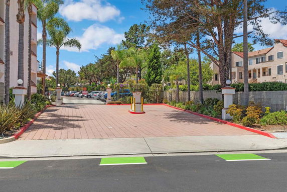 Outdoor parking area with entrance gate and trees surrounding.