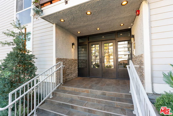 Entrance of a building with double glass doors and tiled steps.