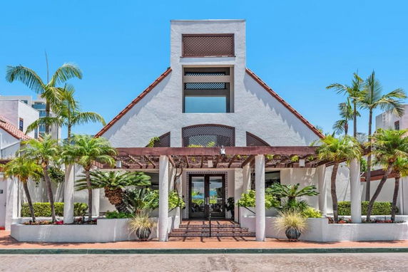 Front view of a building with a triangular roof and a pergola entrance.