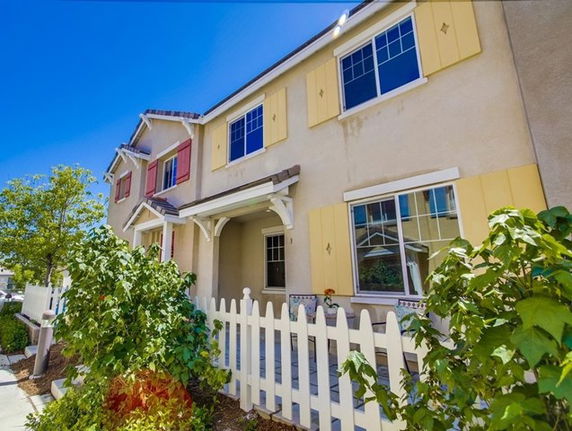Front view of a two-story house with colorful window shutters and a white picket fence.