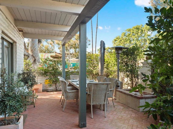 Outdoor patio area with a table, chairs, and surrounding greenery.
