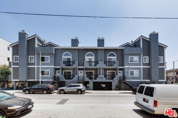 Front view of a multi-story residential building with a gray facade and multiple balconies.