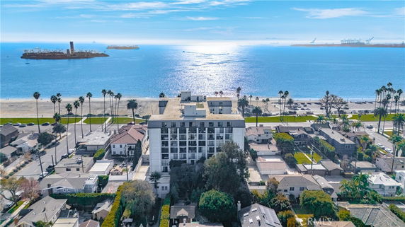Panoramic view of a beachfront building with surrounding homes and ocean in the background.