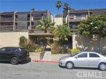 Front view of a multi-story residential building with balconies and palm trees.