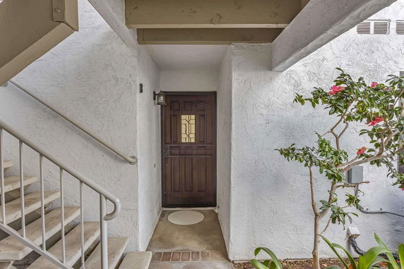 Front view of a house entrance with a wooden door and adjacent staircase.