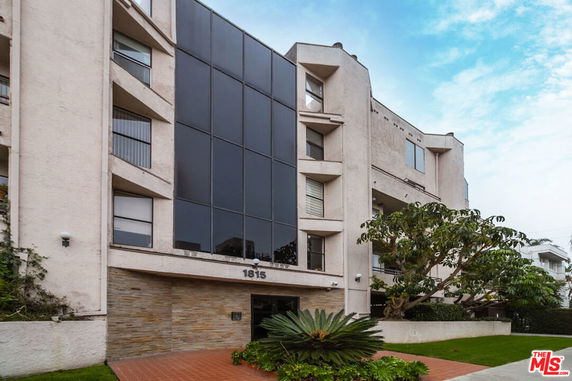 Front view of a multi-story building with large black window panels and balconies.