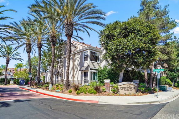 Corner view of a two-story residential building with palm trees and sign.