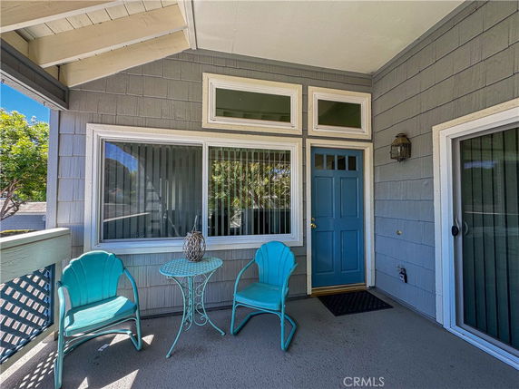 Front view of a house with a blue door and windows, featuring outdoor seating.