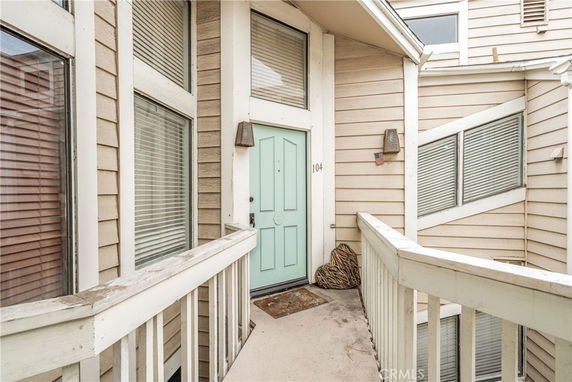 Front view of a house entrance with a light-colored door and surrounding windows.