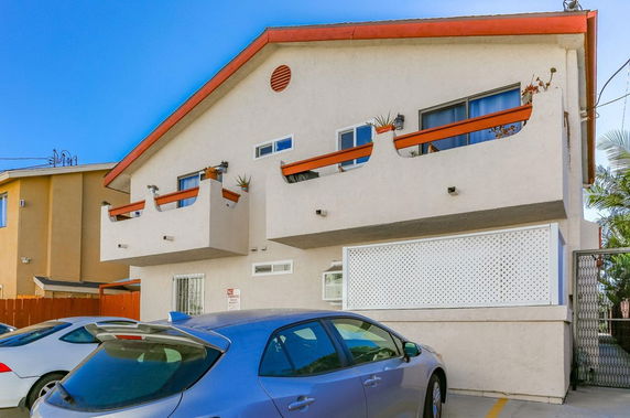 Front view of a two-story building with balconies and a parking area.