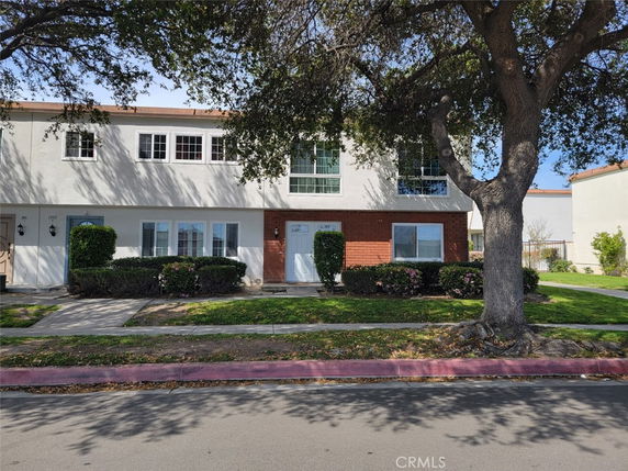 Front view of a two-story townhouse with a mix of brick and stucco exterior.