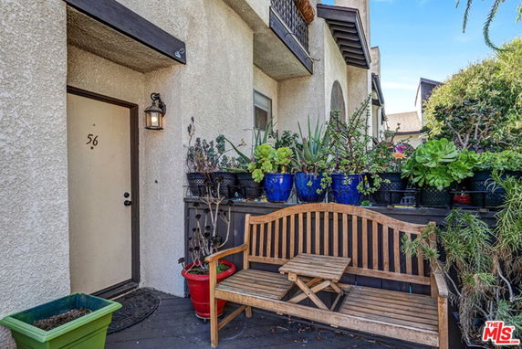 Front view of a house with potted plants and a wooden bench near the entrance.