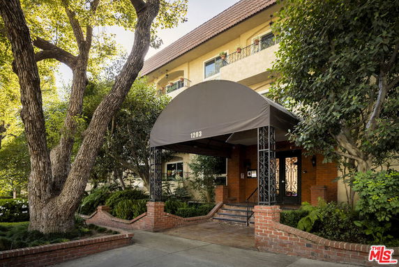 Front view of a multi-story building with a covered entrance and brick pillars.