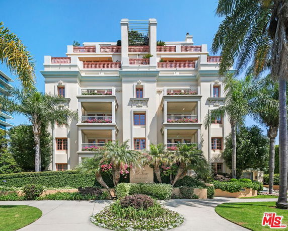 Front view of a multi-story building with balconies and decorative plants.