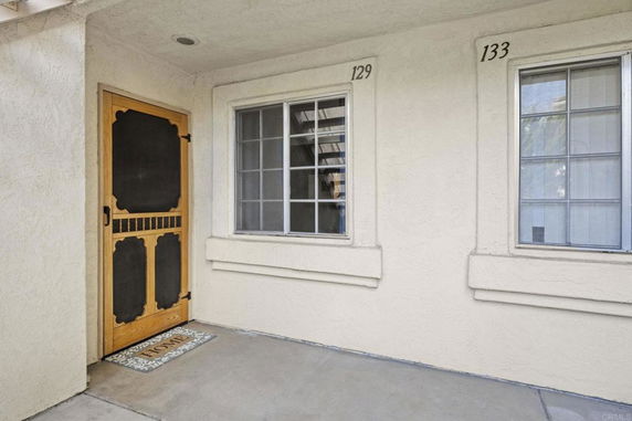 Entryway of a building with two numbered windows and a screen door.