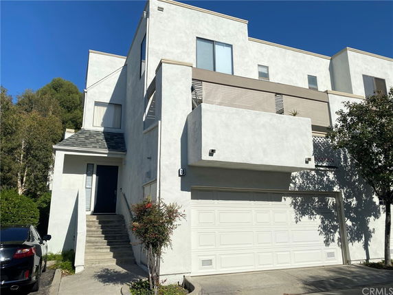 Front view of a modern multi-story house with a white exterior and garage.