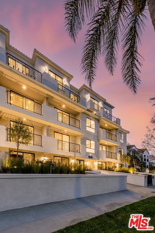 Front view of a multi-story residential building with balconies at sunset.
