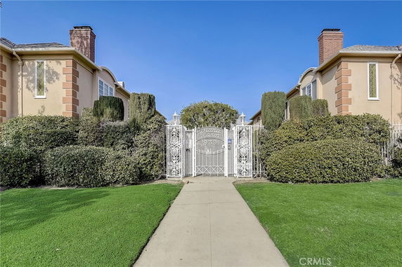 Front view of a residential building with two chimneys and a decorative gate.