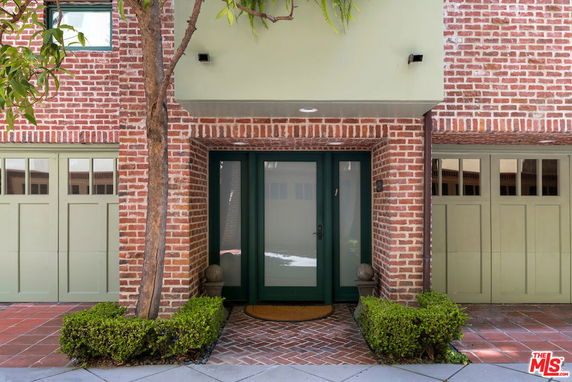 Front view of a house with a brick exterior and green garage doors.