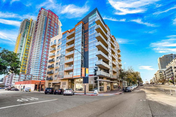 Front view of a multi-story residential building with balconies and glass facade.