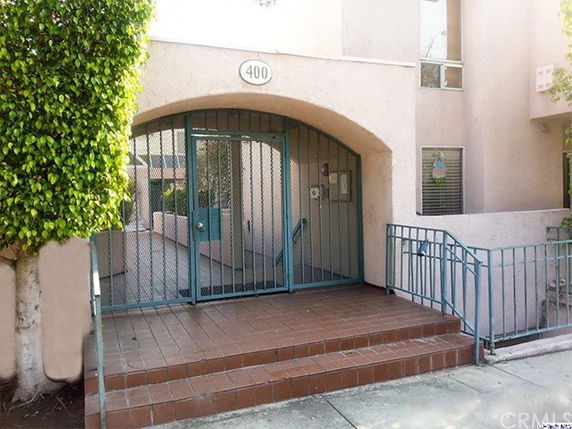 Front view of a building entrance with stairs and a gated door.