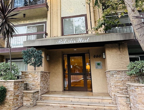 Front view of a multi-story building entrance with stone pillars and glass door.