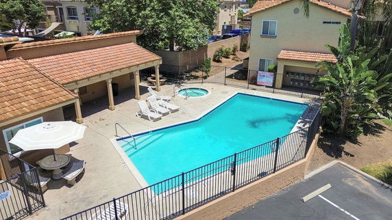Outdoor swimming pool area with lounge chairs and an adjacent small building.