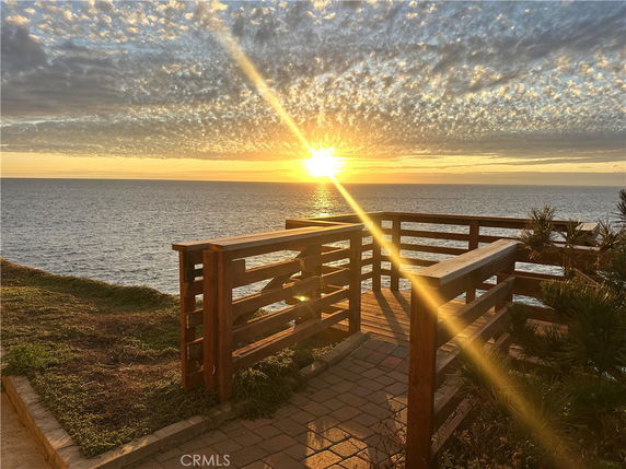 Panoramic view of the ocean with a wooden deck at sunset.