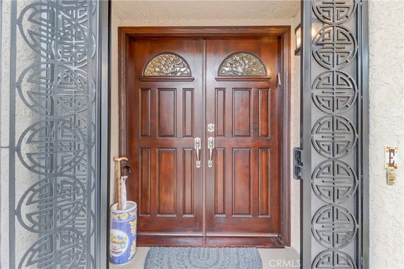 Front view of a house entrance with a wooden double door and decorative metal screen.