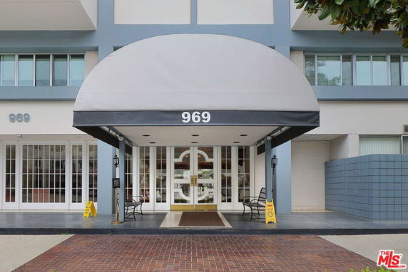 Front view of a building entrance with a gray awning and glass doors.