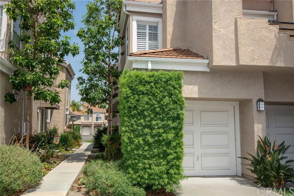 Front view of a townhouse with a garage and a green plant covering part of the exterior wall.