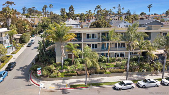 Front view of a multi-story building with palm trees and surrounding neighborhood.