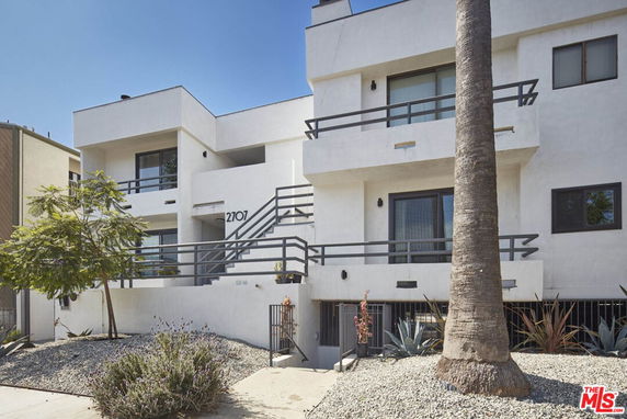 Front view of a modern multi-story building with balconies and a minimalist design.