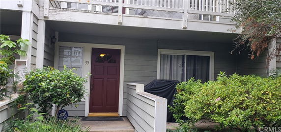 Front view of a house with a small porch and a red door.