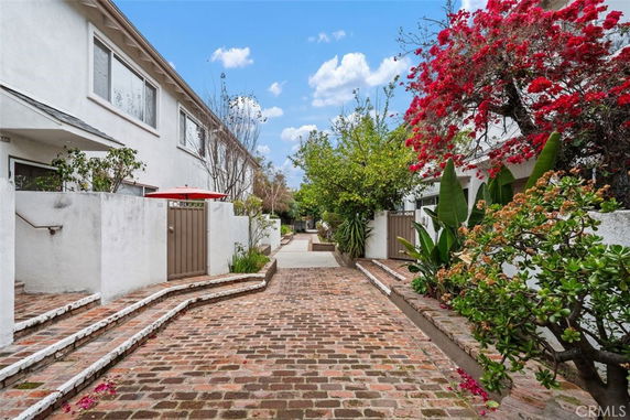 Front view of a residential building with a brick walkway and surrounding foliage.