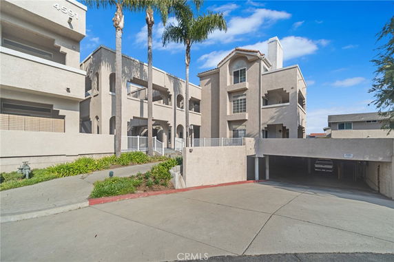 Front view of a multi-story residential building with arches and balconies.