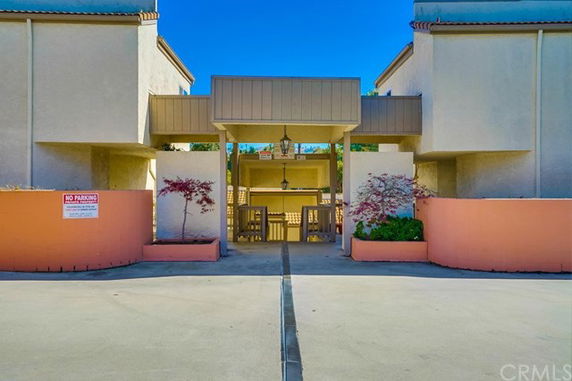 Front view of a building entrance with a covered walkway and seating area.